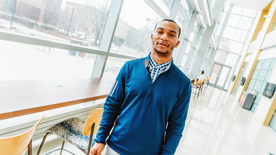Student standing by windows in College of Business building