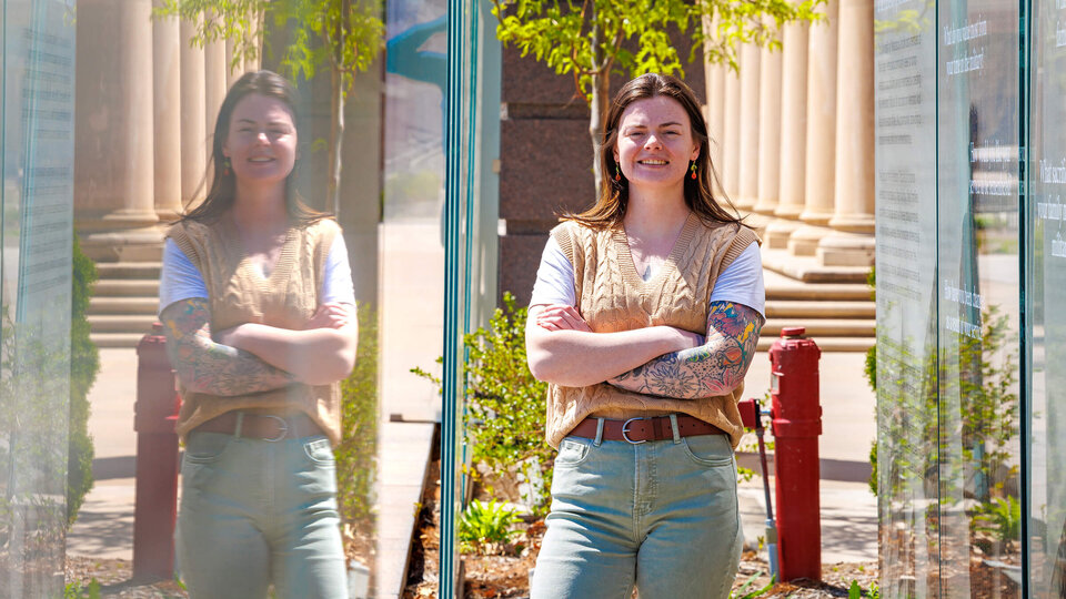 Student standing by Veterans Tribute with reflection in glass