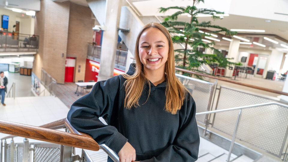 Student in black sweatshirt standing by railing in East Campus Union