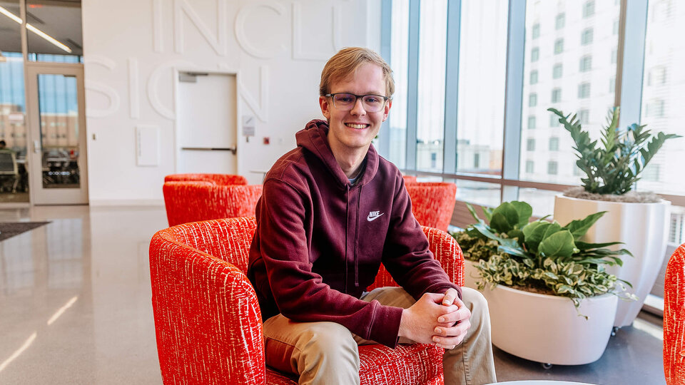 Student in hoodie sitting in orange chair