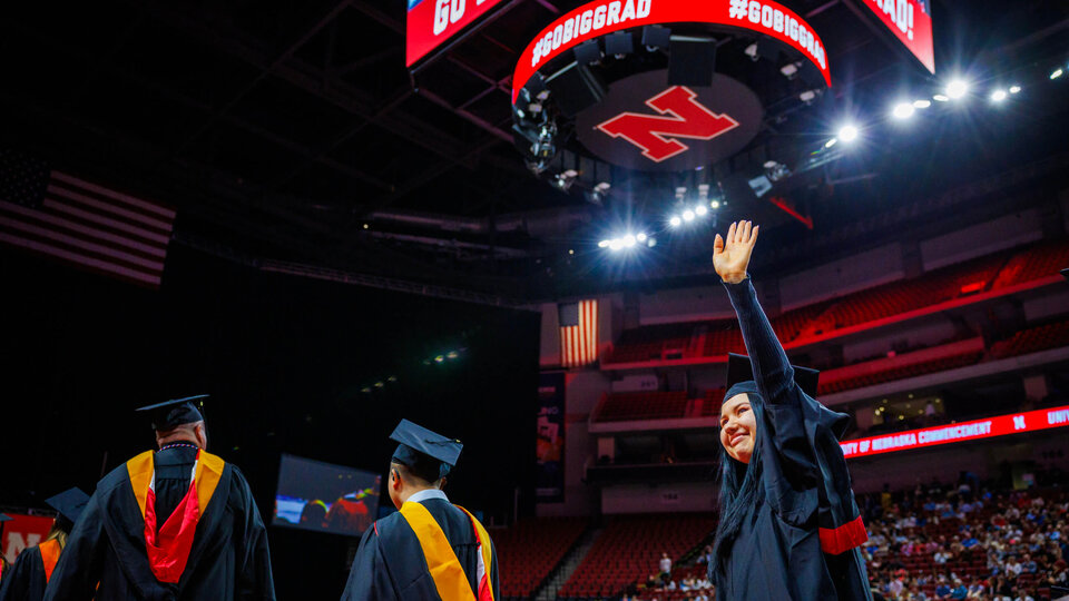 Student waving at graduate commencement in Pinnacle Bank Arena