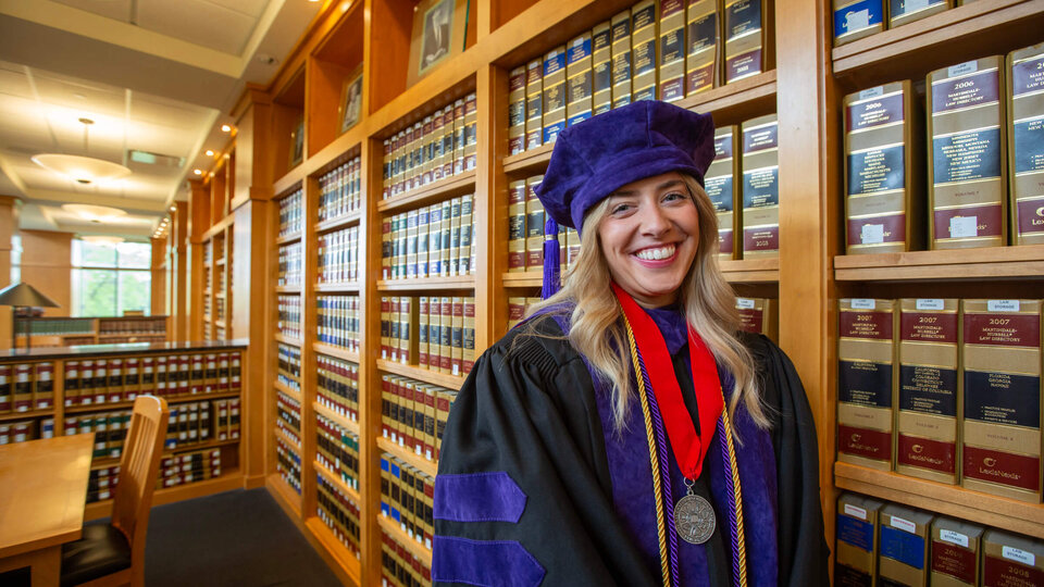 Law graduate wearing robe in Schmid law library