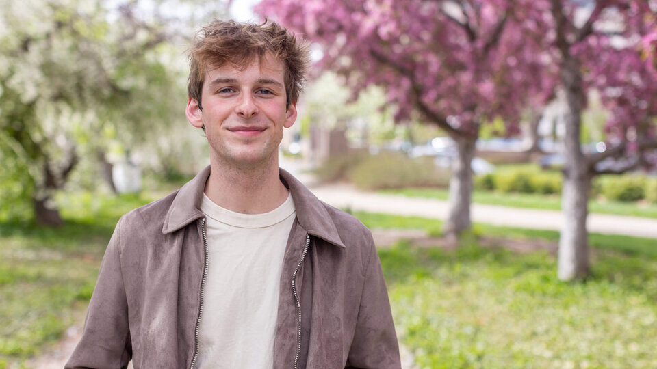 Student standing outside on campus in front of blooming trees