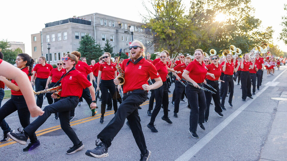 Marching band members dancing and cheering during Homecoming parade