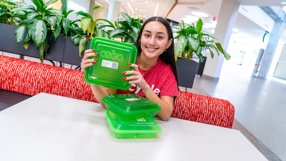 Student holding green recycled plastic storage containers