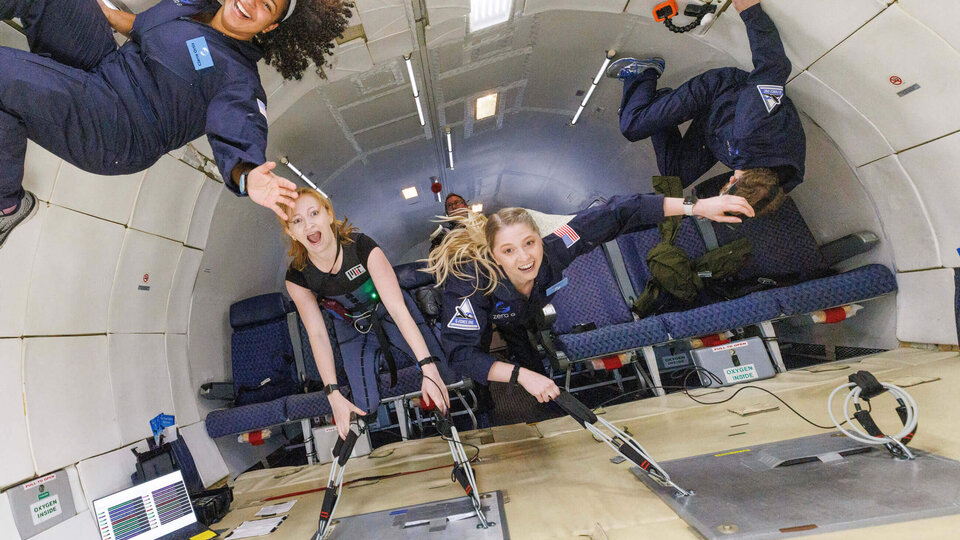 Student interns with NASA float in plane during zero gravity test