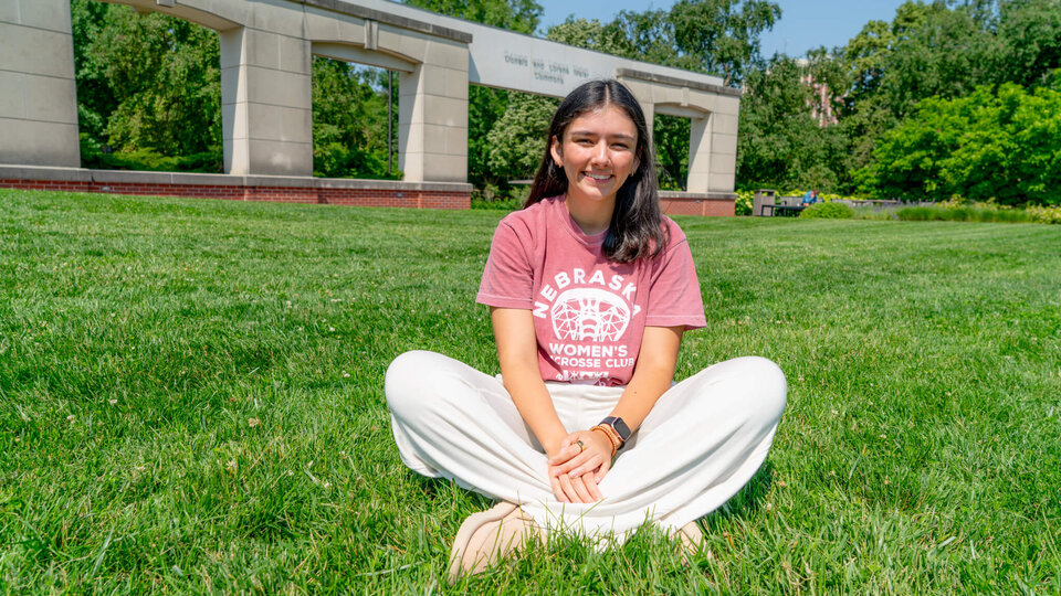 Student sitting in grass quad behind union
