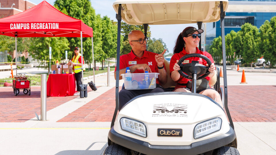 Staff members in a golf cart help students on move-in day