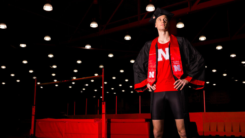 Student in track clothes and graduation cap standing on indoor track