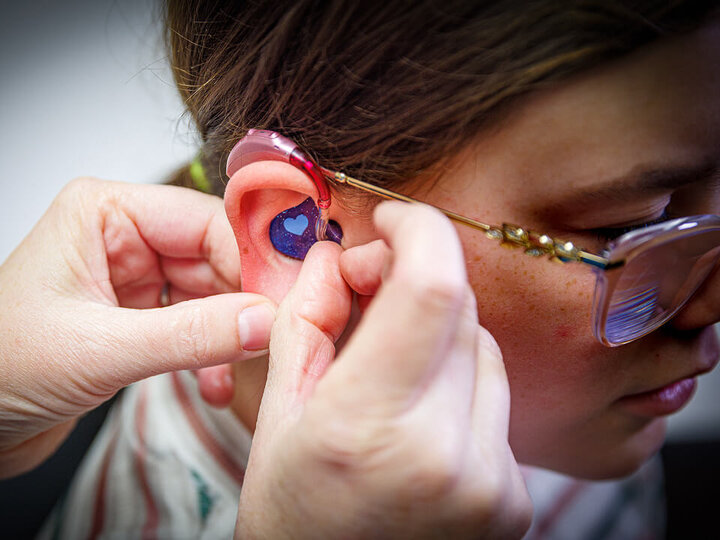 Doctor checks fit of hearing aid