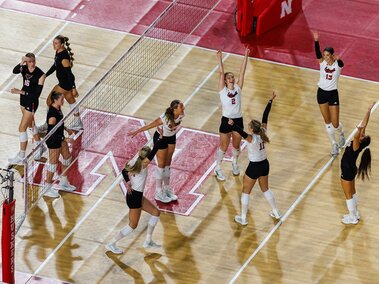 Overhead angle of the Husker volleyball team celebrating the match point in a 3-0 sweep over the U N O Mavericks