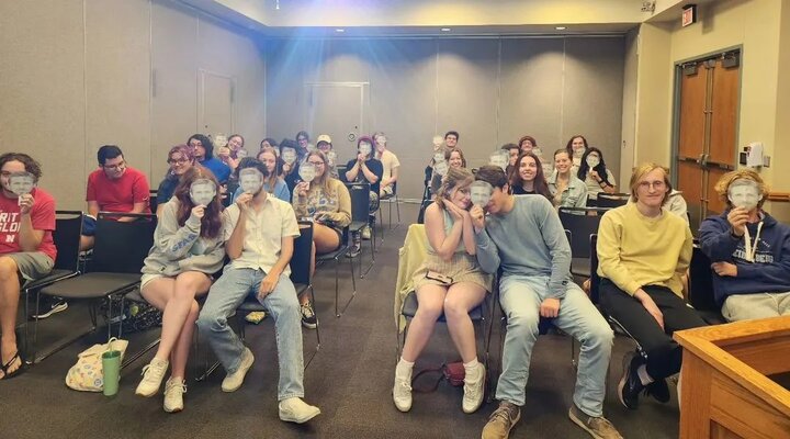 Students hold up cut outs of Ryan Goslings face during a recent movie screening