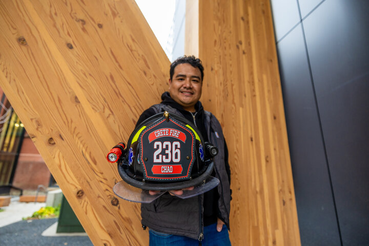 Landon Chao holding out his firefighting helmet. 