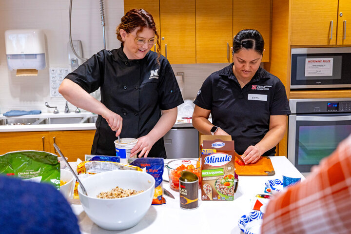 Ellyn McCarter, dietician and nutrition manager with Dining Services, shows students how to core a tomato during a cooking demonstration at the University Health Center. Participants learned to prepare both McCarter's southwest grain bowl recipe and a chicken and vegetable ramen recipe developed by Sarah Keegan, Nebraska Medicine dietician, and did a taste test of dairy- and plant-based chocolate milks. 2861: Sarah Keegan (left), Nebraska Medicine dietician, holds up packaging for microwaveable and stovetop