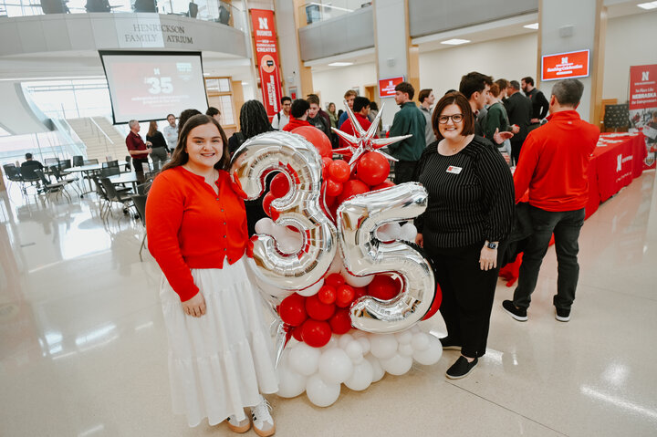 Mallory Krenk and Amanda Metcalf smile for a photo in the Nebraska College of Business with 35 balloons celebrating their newest achievement.