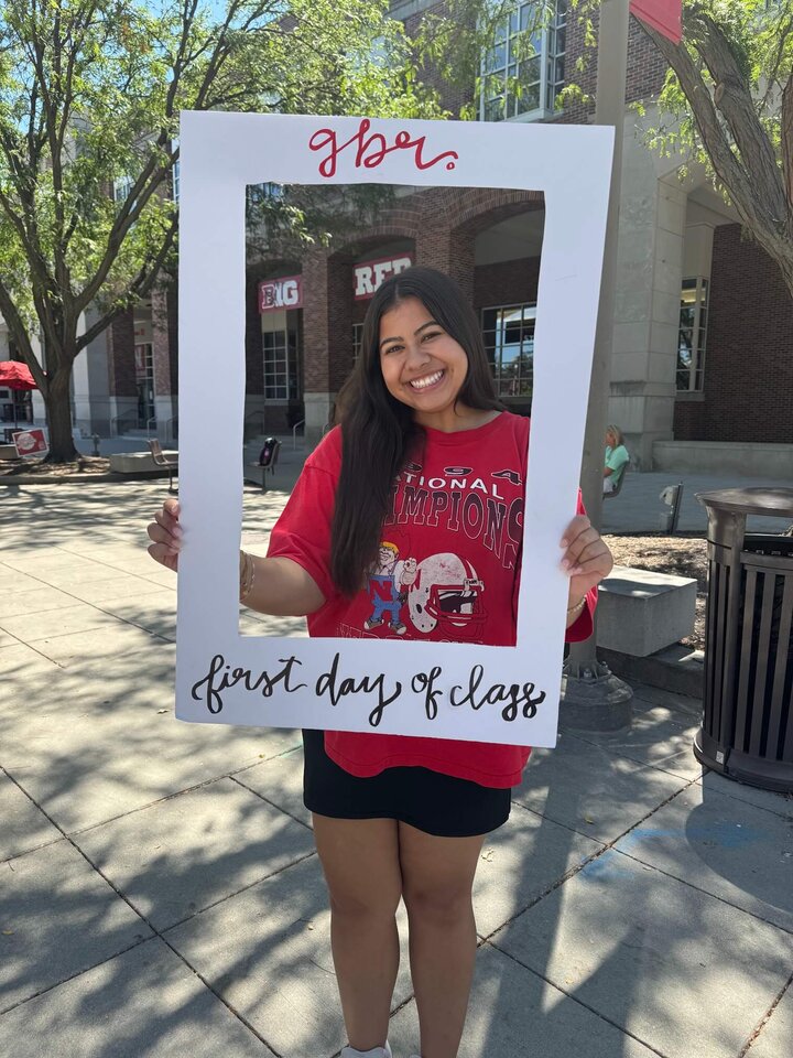 Jenny Castor poses with a white frame that reads "gbr" at the top and "first day of class" on the bottom.