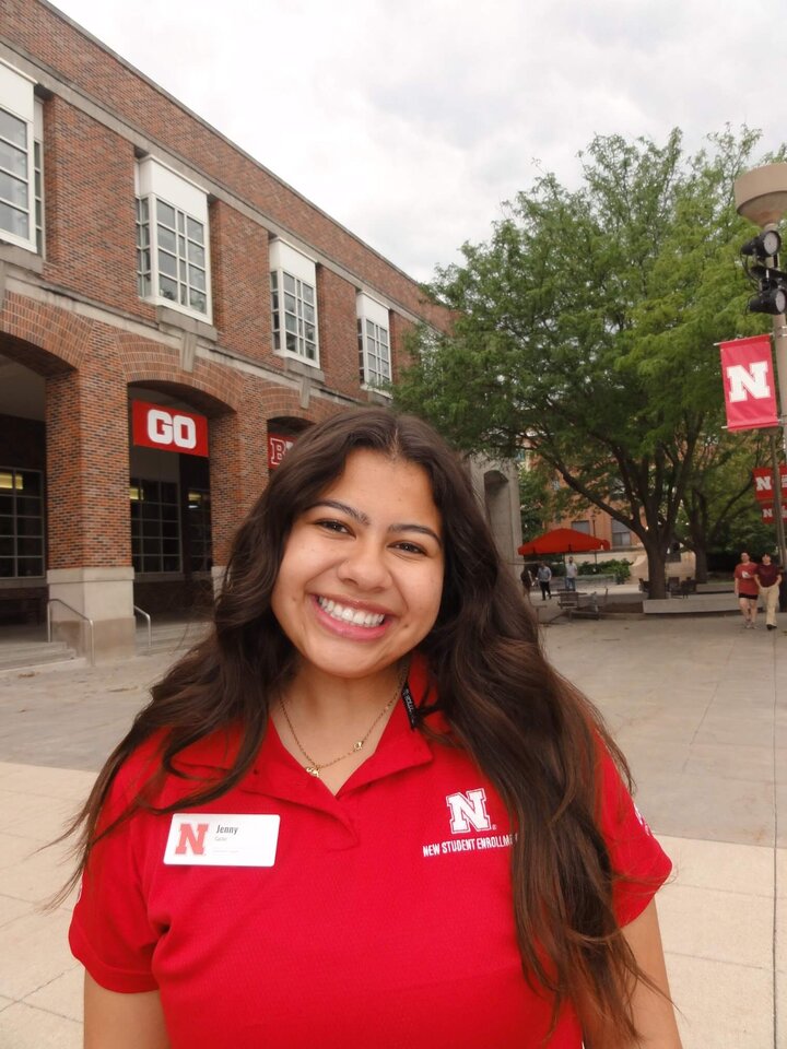 Jenny Castor smiles in a red New Student Enrollment polo during the summer.