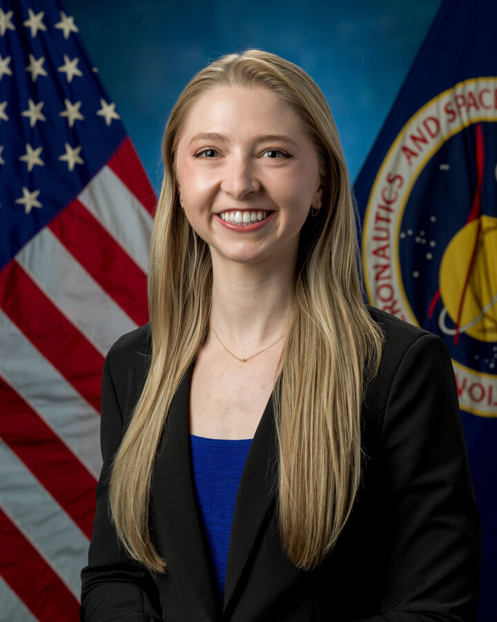 Allison Porter Carpenter smiles in front of the American flag for a professional headshot.