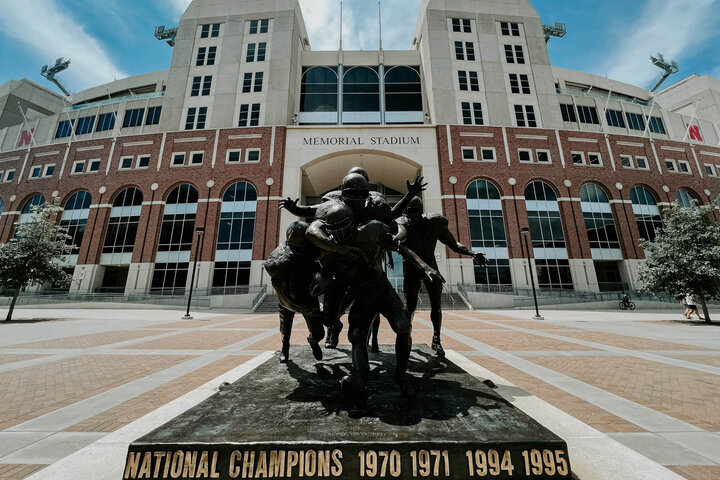 Football player statue in front of Memorial Stadium with championship years engraved.