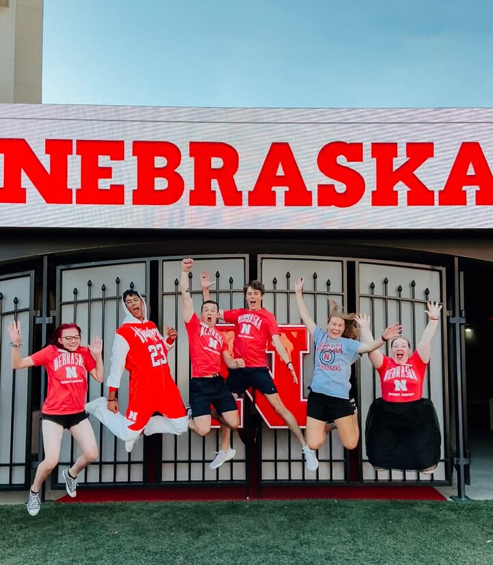 Phoenix, third from left, jumps in the air with friends in front of the tunnel in Memorial Stadium