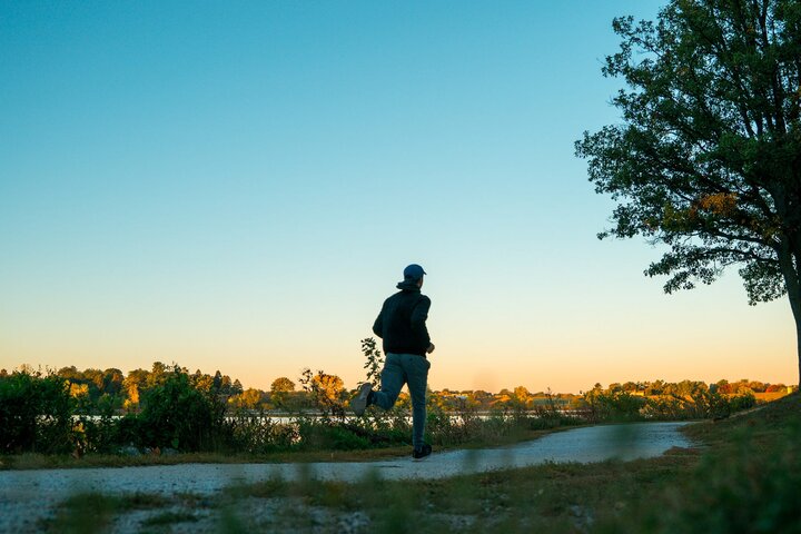 A person running on a path through Holmes Lake as the sun rises