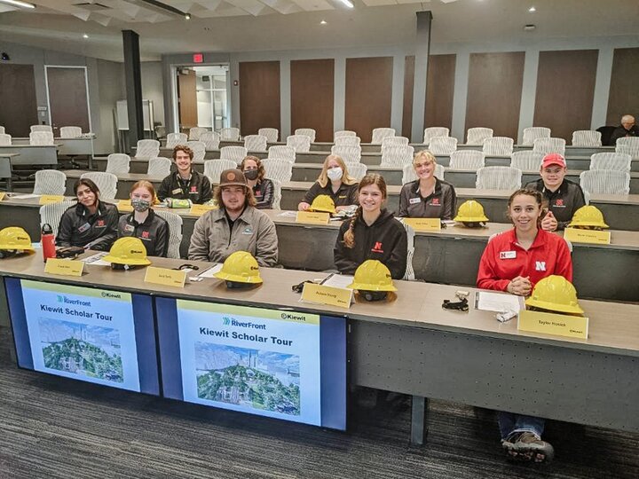 Kiewit Scholars sit at tables with hard hats before a tour