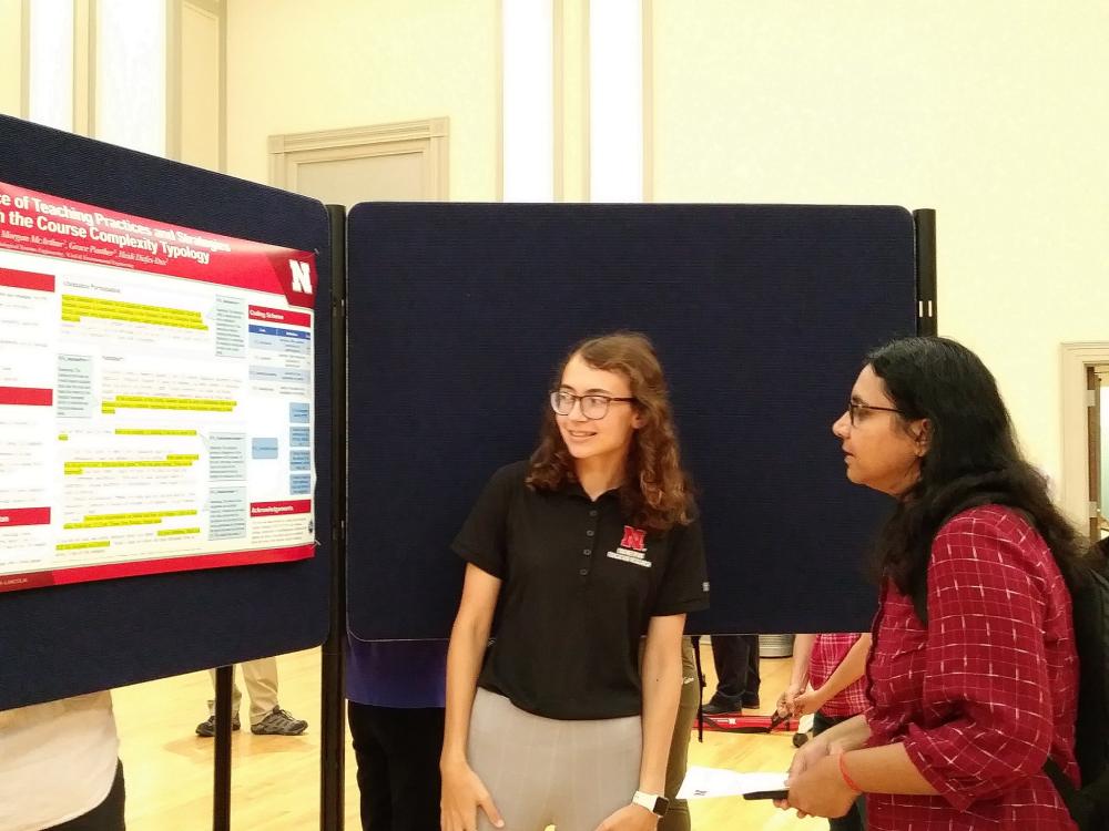 Summer undergraduate engineering education researcher Dorian Bobbett (left) shares her research poster with an interested graduate student during the Summer Research Symposium in August of 2022.